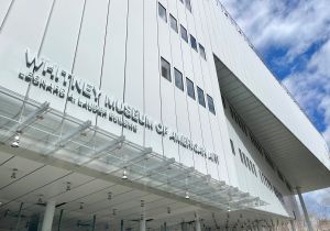 Exterior view of the Whitney Museum of American Art’s Leonard A. Lauder Building, showing its angled steel facade, glass canopy and upper-level cantilever against a partly cloudy sky.