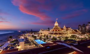 An aerial shot of a massive hotel complex completely lit up in twinkle lights, with the sky at dusk.