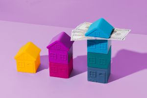 Three houses next to each other, each one progressively taller. The roof of the tallest house is bisected by cash.