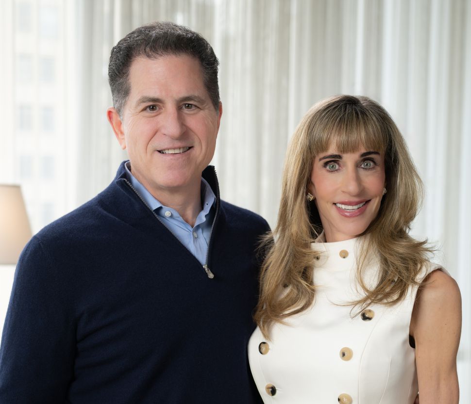Man in black sweater and woman in white dress pose together