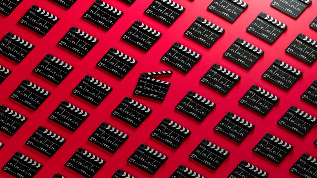 repeating pattern of film slates against a red background; a slate in the middle is open